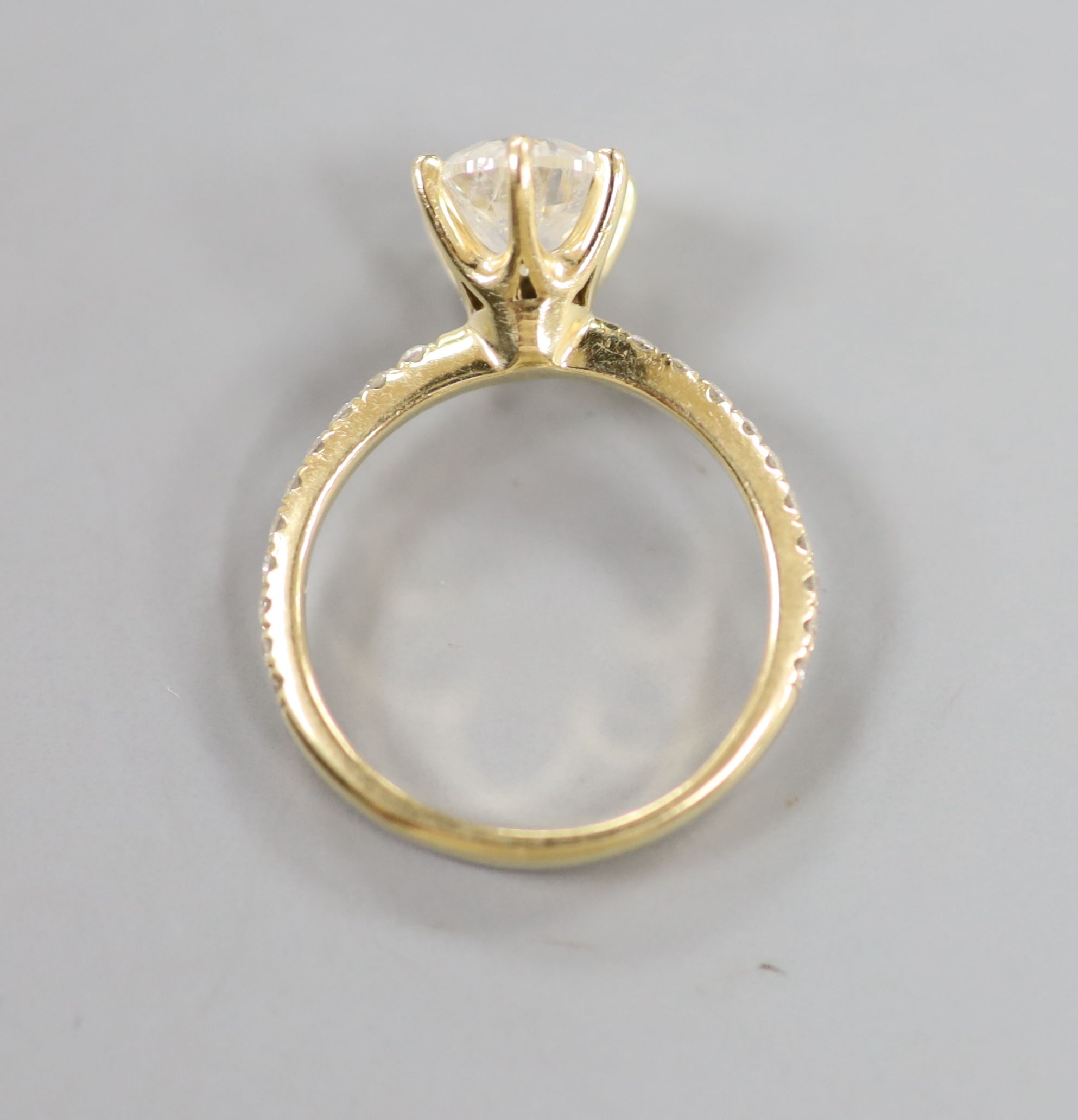 A modern 14kt yellow metal and single stone diamond ring, with diamond chip set shoulders